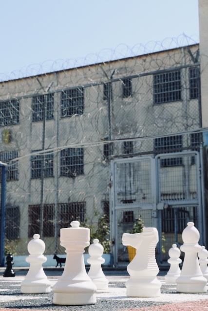 Large chess pieces in an outdoor area in front of a secured building