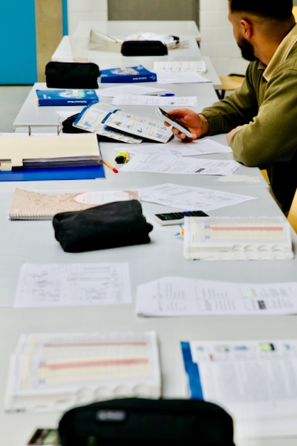 Learning materials and a participant at a classroom table at JVA Heinsberg