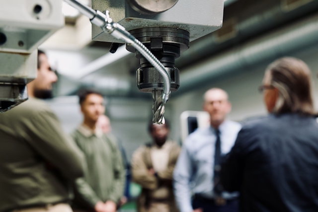 People in a workshop at JVA Heinsberg, with a milling machine in the foreground